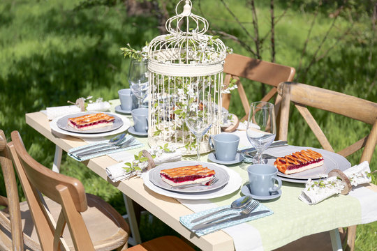 Beautiful table setting and cage with flowers in garden