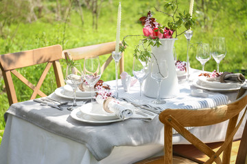 Table setting and jug with flowers in garden