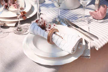 Photo sur Aluminium Pique-nique Assiette avec serviette et branche de fleurs sur table de fête servie