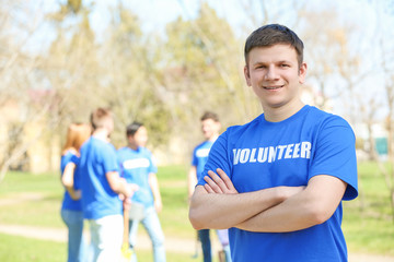 Naklejka premium Handsome young volunteer with team outdoors