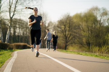 Young woman jogging at park on track path to finish