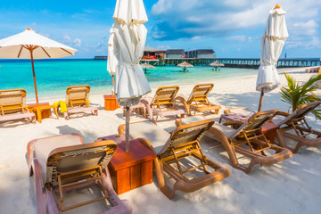 Beach chairs with umbrella at Maldives island with white sandy beach and sea .