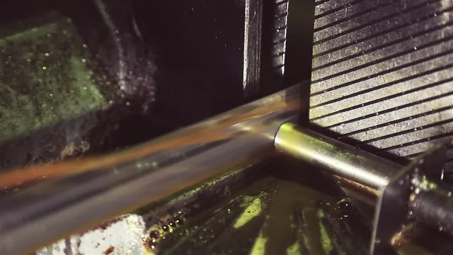 Metal processing machine. A metal saw cuts off a thin steel pipe, which is clamped in a vice. Cutting of metal by a metalworking machine at a steel mill.