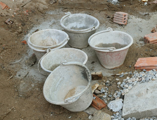 Old cement mixer bucket placed on a cement floor in the construction site.