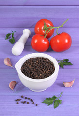 Black pepper in mortar and vegetables on purple boards