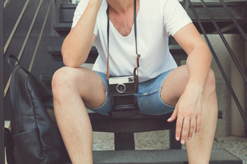 Hipster guy posing outdoors with old camera.