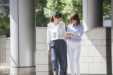 Two women are walking outside the office on a fine day