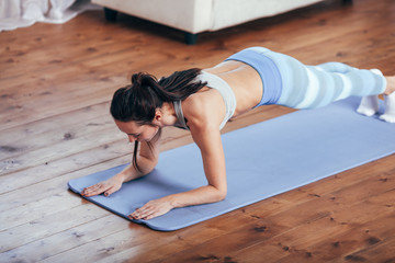 Slim fitness young woman doing plank exercise at home .