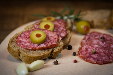Sandwiches with salami and olives on wooden board