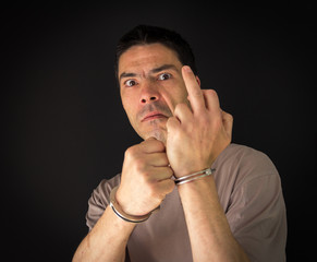 A criminal in handcuffs showing the middle finger