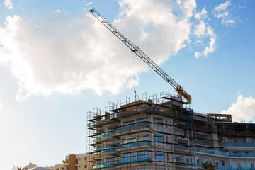 Building crane and building under construction against blue sky