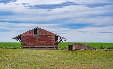 Fototapeta na wymiar Red Barn in a Green Field 