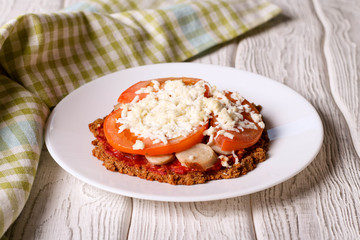 Mini pizza with sausage, cheese and tomato