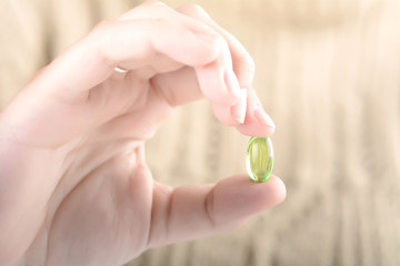 Female hand holding a pill.
