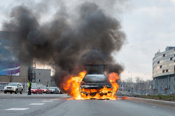 A few minutes in the street burnt car. Traffic is stopped. Firefighters eliminate fire.
