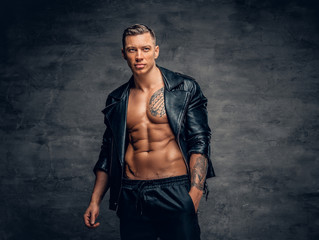 A man with tattoo on a chest, dressed in a black leather jacket.