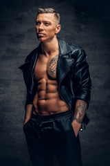 A man with tattoo on a chest, dressed in a black leather jacket.