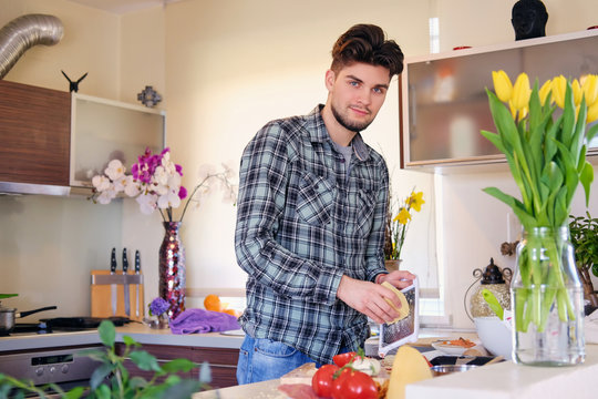 A handsome bearded male dressed in a fleece shirt making salad from vegetables.