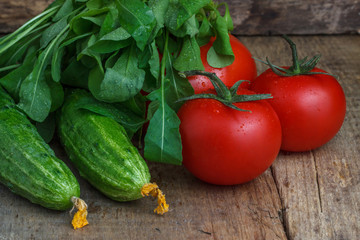 Tomatoes and cucumbers with salad on the background of wood