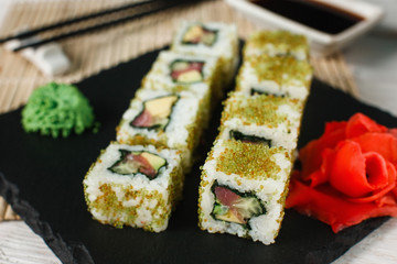 Set of sushi rolls with salmon, avocado, cucumber and green tobiko caviar. Healthy Japanese food, traditional seafood.