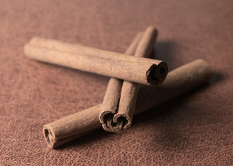three cinnamon sticks on brown background