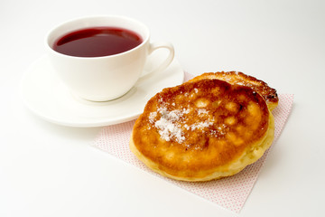 Cup of tea with pancakes on a white