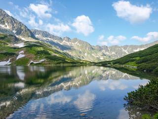 Naklejka na ściany i meble Mountain lake and the mountain slope reflected in it