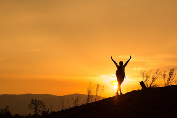 Woman backpacking to watch the sunset.Silhouette Standing fly like a bird