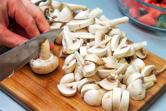 Сhef cutting mushrooms on wooden cutting board