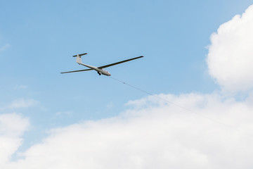 Glider towed on a rope flying on a blue sky background.