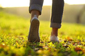 sneaker and jeans walking on the grass with beautiful sunset light
