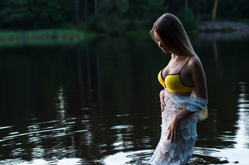 young teenager girl in white dress and yellow swimsuit standing in water