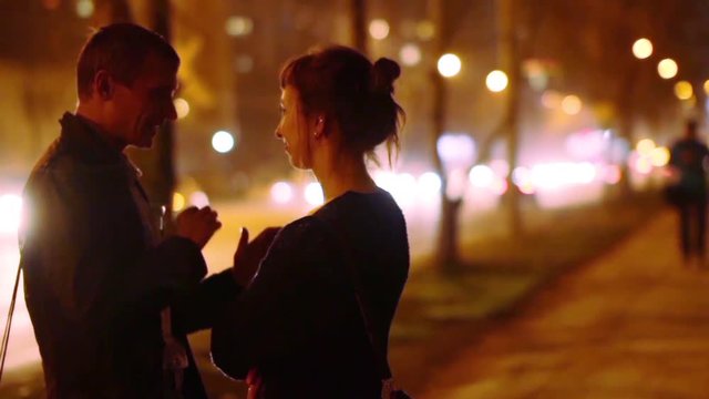 A guy and a girl talk and walk around the night city