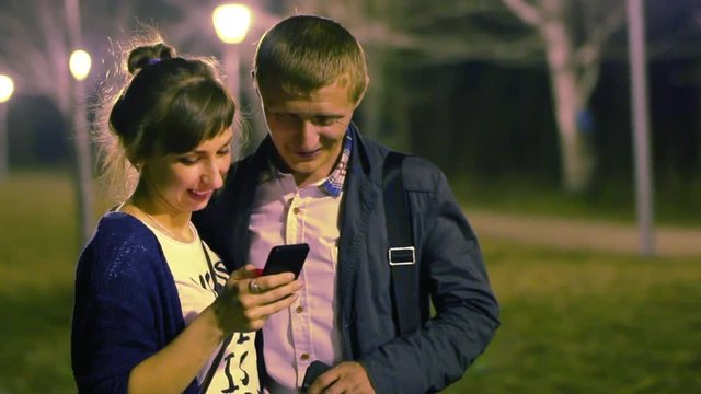 A guy and a girl talk and walk around the night city