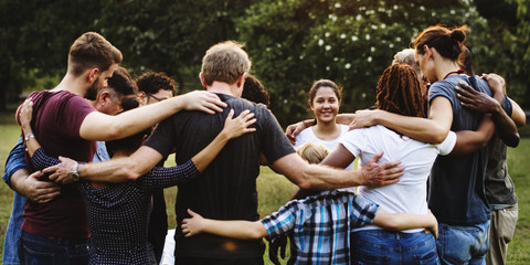 Group of people huddle together in the park - obrazy, fototapety, plakaty