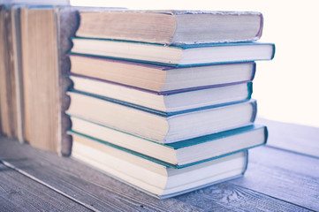 Piles of old books on a wooden table. Vintage toning.