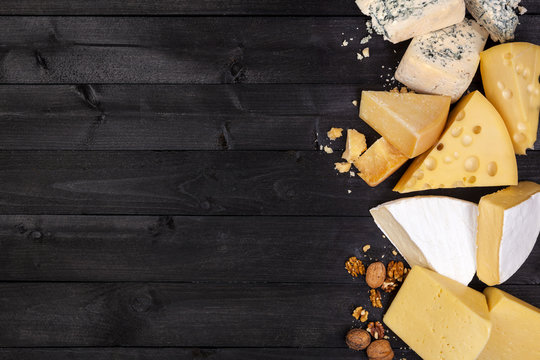 Various types of cheese on black wooden table. Top view. Copy space.