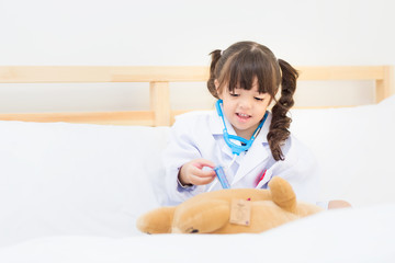Fototapeta premium Little girl kid imagination works doctor in future by injection a toy practice