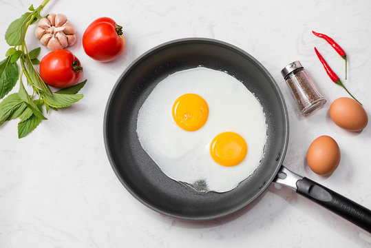 Fried eggs in a frying pan with cherry tomatoes and bread for breakfast