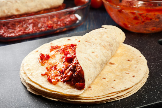 Preparation traditional mexican enchiladas with chicken meat, spicy tomato sauce and cheese