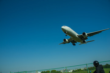 着陸態勢のジェット旅客機を見上げる