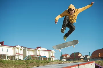 Schilderijen op glas A teenager skateboarder does an flip trick in a skatepark on the outskirts of the city © yanik88