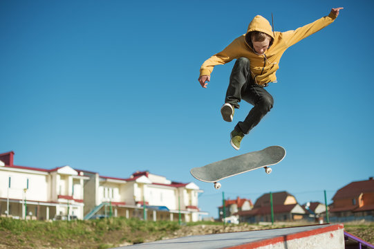 A teenager skateboarder does an flip trick in a skatepark on the outskirts of the city