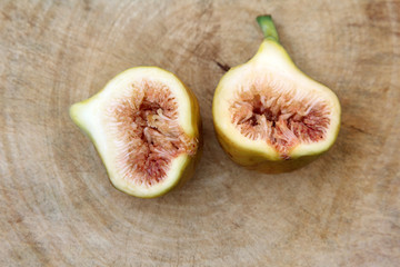 Common fig fruits cut open showing the flesh on wooden background, Top view.