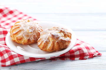 Homemade profiteroles with cream on white wooden table