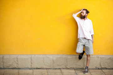 Obraz na płótnie Canvas Tattooed fashion bearded hipster on yellow wall posing outdoor