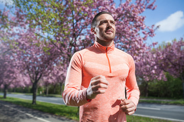 Fototapeta premium Joggender Mann im Park im Frühling im Sonnenschein