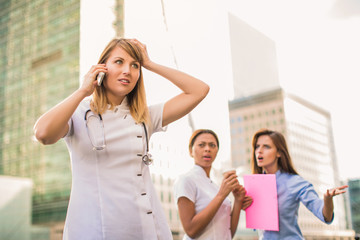 Young surprised doctor speaks the phone against the background of two young surprised nurses who...