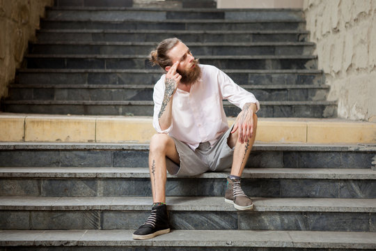 Stylish tattoed and bearded guy posing outdoor in the city