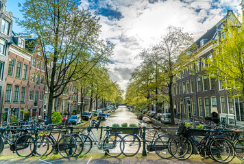 Fototapeta premium Amsterdam, The Netherlands, April 22, 2017: Small quiet canal with bikes on bridge in front in the Center of Amsterdam